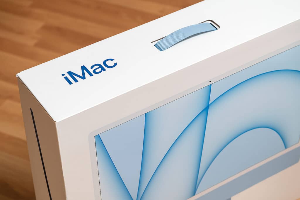 Boîte d’un iMac 24 pouces M3 avec poignée bleue, prêt à être transporté ou revendu
