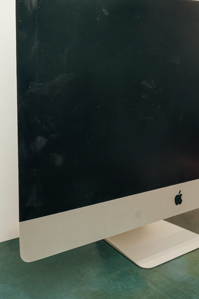 Écran d’iMac Apple recouvert de traces de doigts et de poussière, en attente de nettoyage