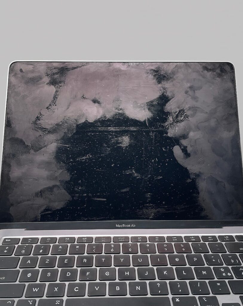 MacBook Air A2179 avec un écran sale et plein de traces de doigts sur fond neutre