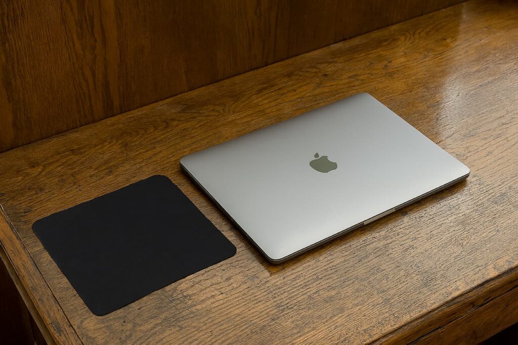 Chiffon à lunettes noir pour nettoyer l’écran d’un MacBook Apple sur un bureau en bois