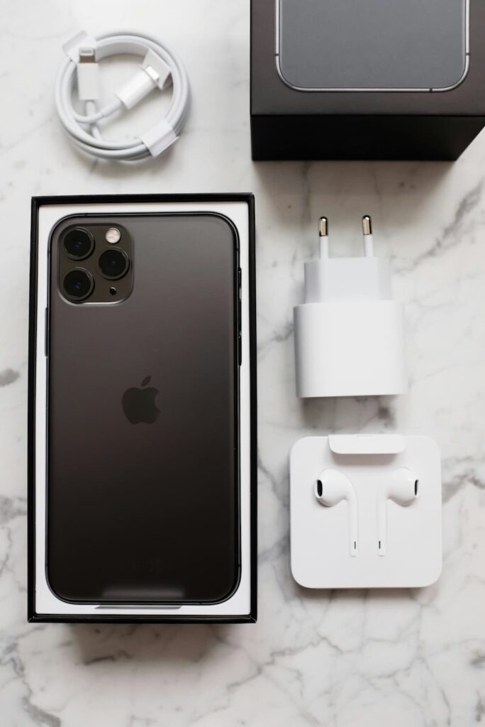 iPhone reconditionné noir avec câble, chargeur et écouteurs dans sa boîte d’origine.