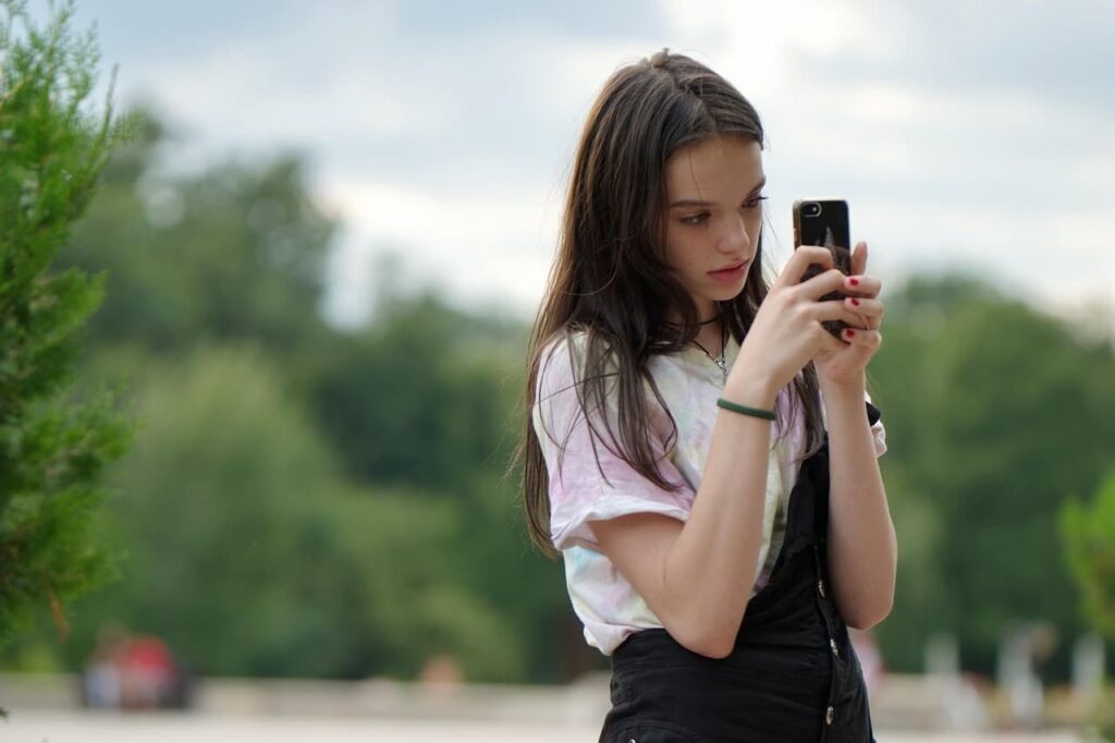 Jeune adolescente concentrée sur son smartphone en extérieur