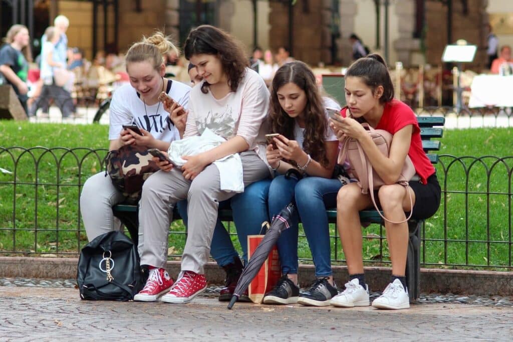 Groupe d’adolescentes utilisant intensément leurs téléphones dans un espace public