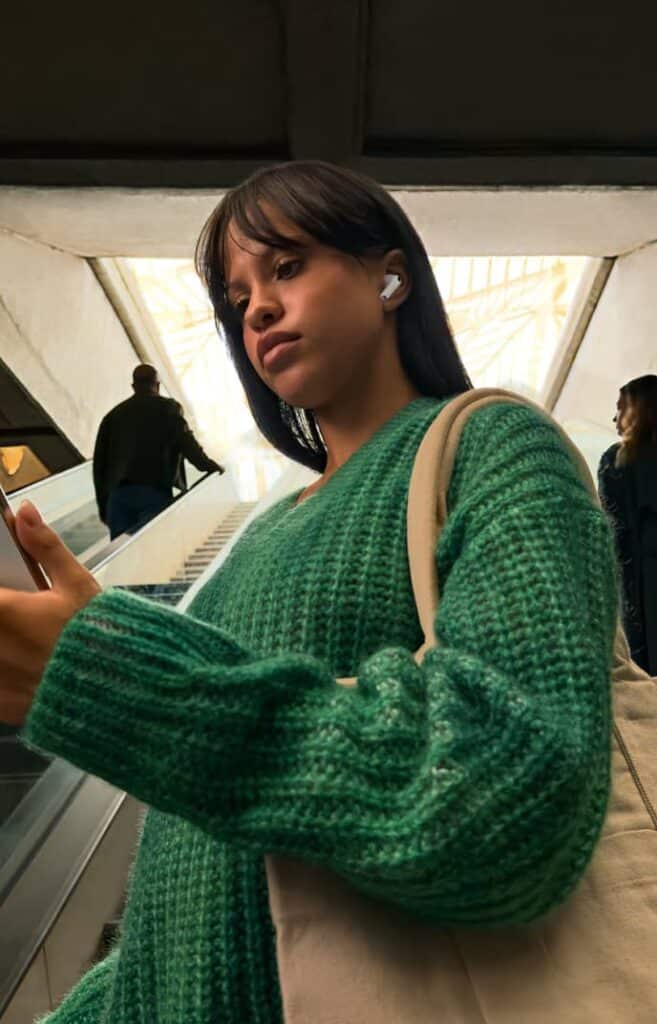 Femme utilisant les AirPods Pro 3 dans un escalator, bénéficiant de l’annulation active du bruit pour profiter de sa musique sans les bruits ambiants.